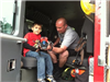 Firefighter Showing Boy Fire Truck Equipment